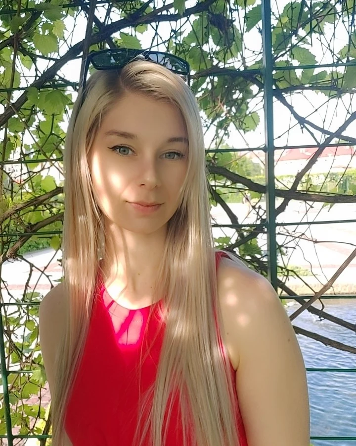 Kasia Sowa outdoors under a vine-covered pergola, in dappled summer light